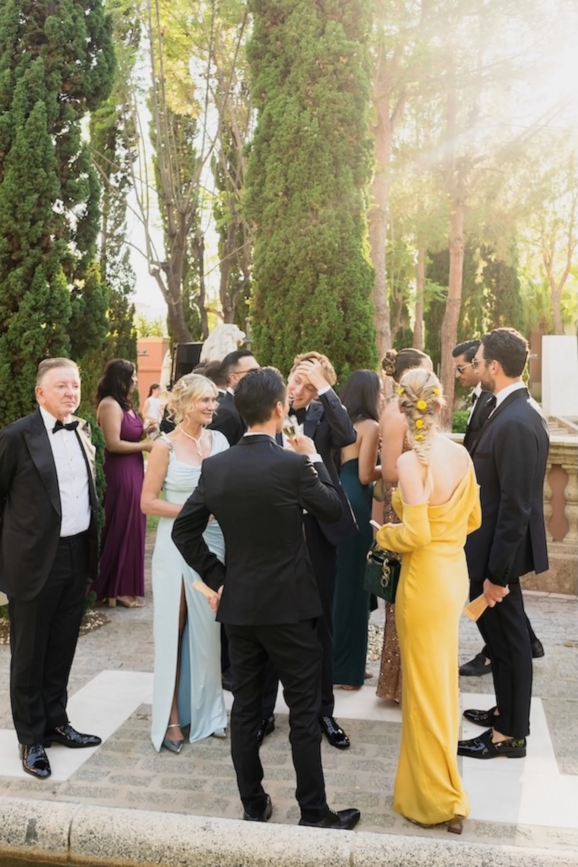 Wedding guests in formal attire gathering in the gardens of an elegant estate