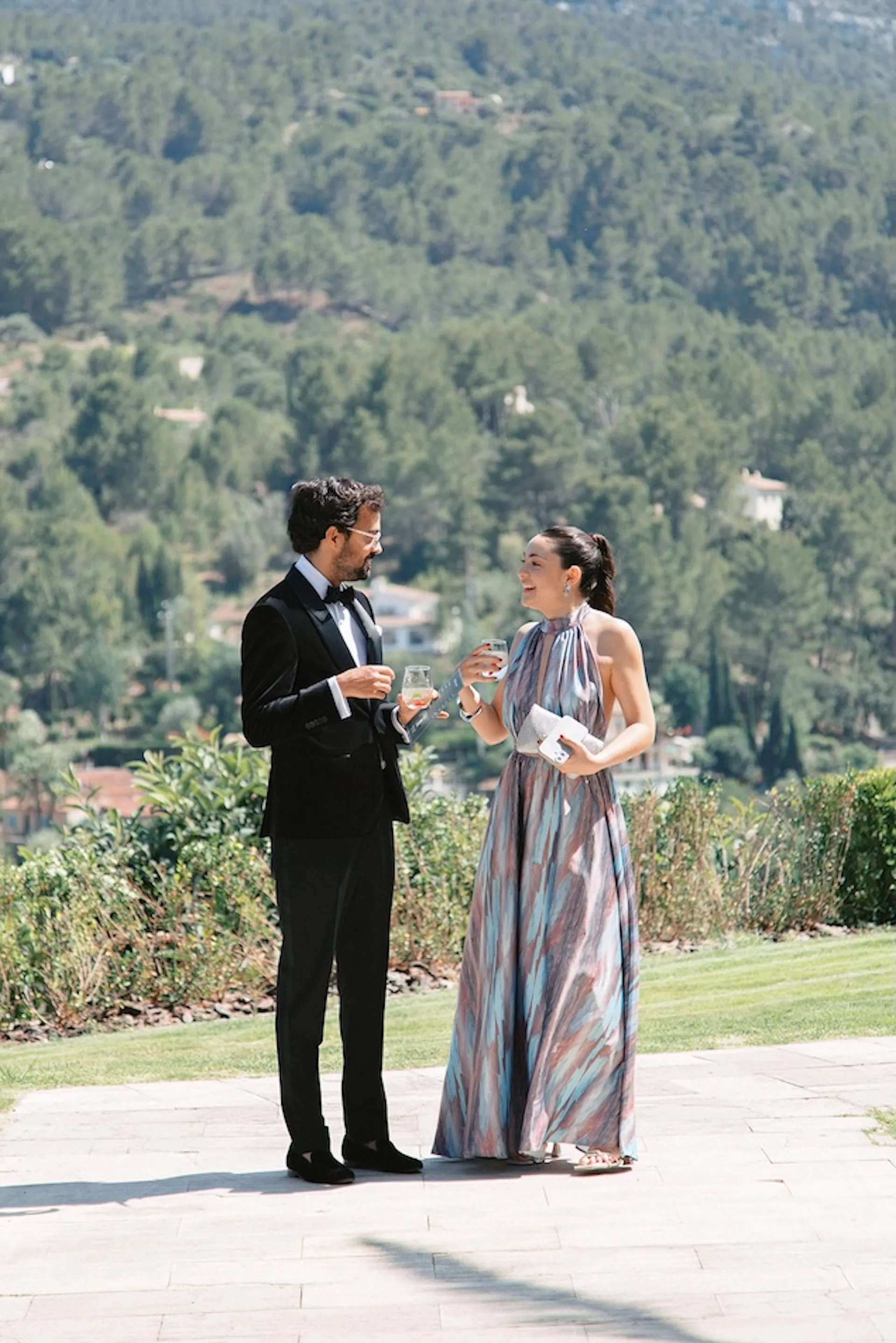 Man in a tuxedo and woman in a long patterned dress at an outdoor wedding celebration
