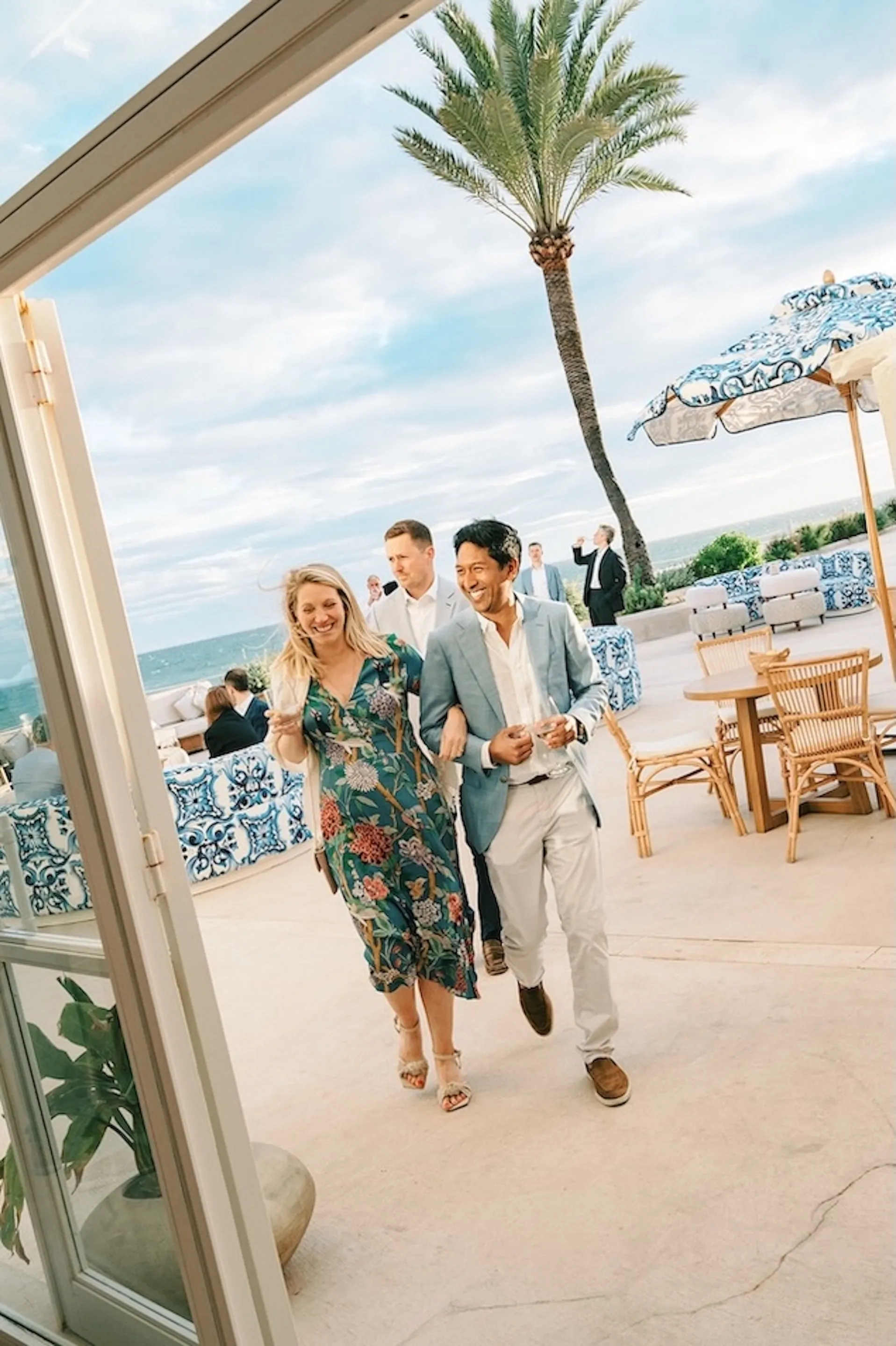 Wedding guests in elegant summer attire arriving at a Mediterranean seaside venue